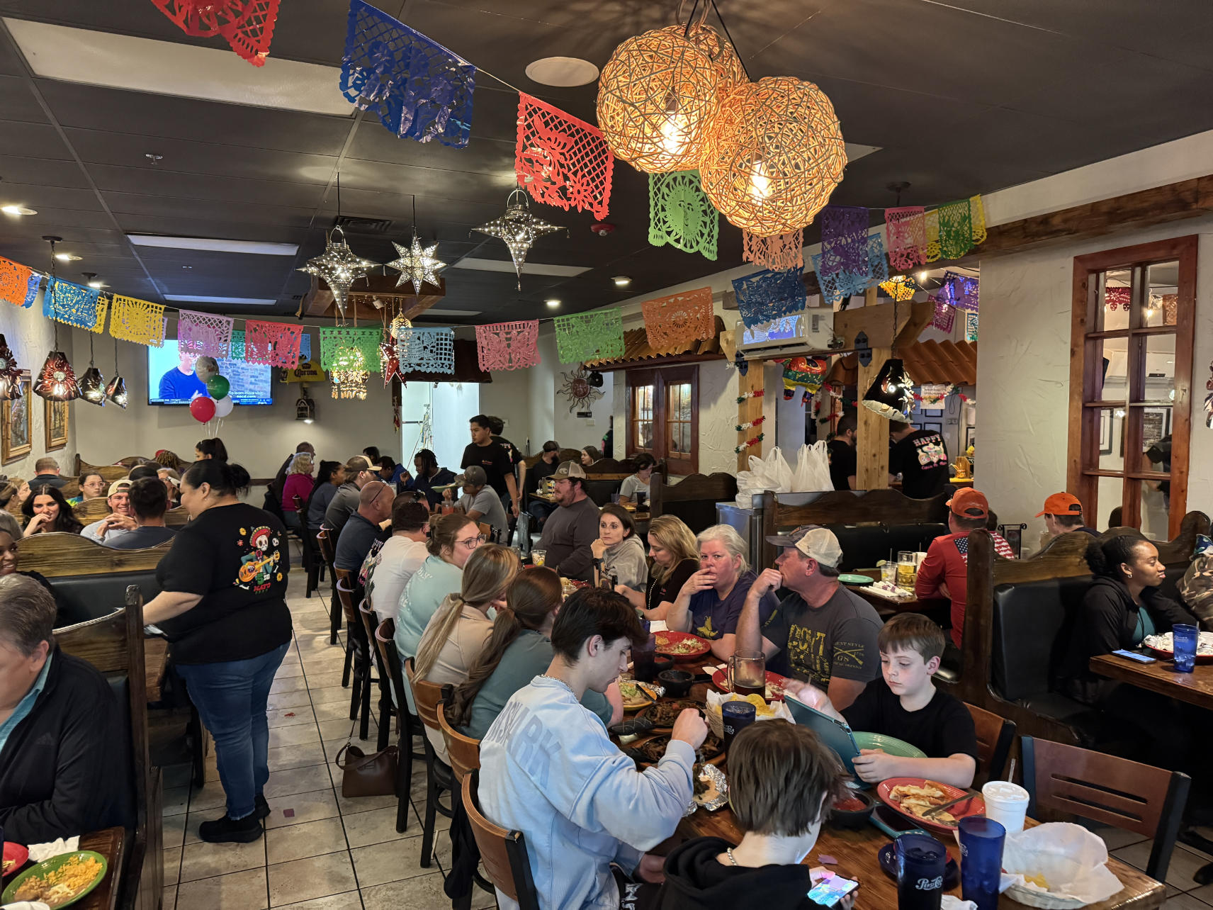 Packed restaurant with families dining under colorful papel picado banners